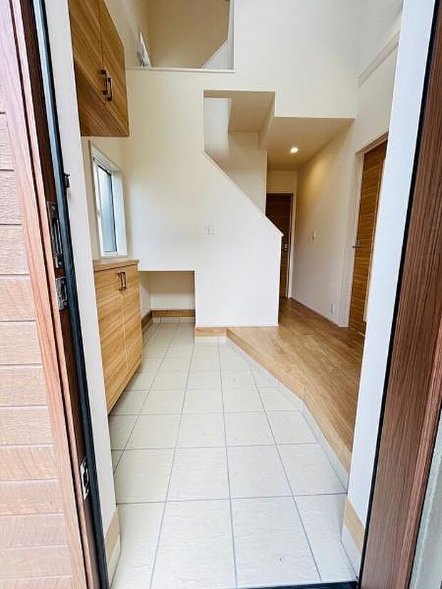 玄関はタイルとフローリングの切り替えが特徴的です。収納スペースも備えられており使い勝手が考えられています。白を基調とした明るい印象の内装です。天井が高く開放感のある空間です。