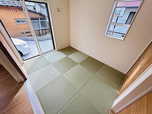 明るい光が差し込む和室です。シンプルな内装が落ち着いた印象を与えます。畳の配置がモダンな雰囲気を演出しています。スライドドアから外へのアクセスも便利です。窓が2面にあるため通風も良好です。