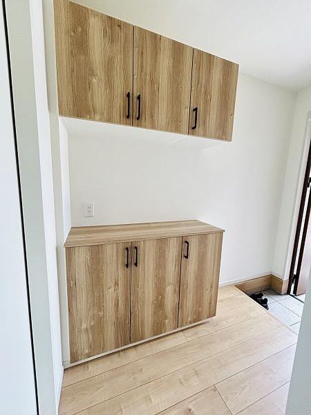 木目調の収納が玄関に自然に溶け込んでいます。白を基調とした空間に明るさが加わり印象が良くなります。収納スペースがしっかり確保されていて玄関周りがすっきりと整います。