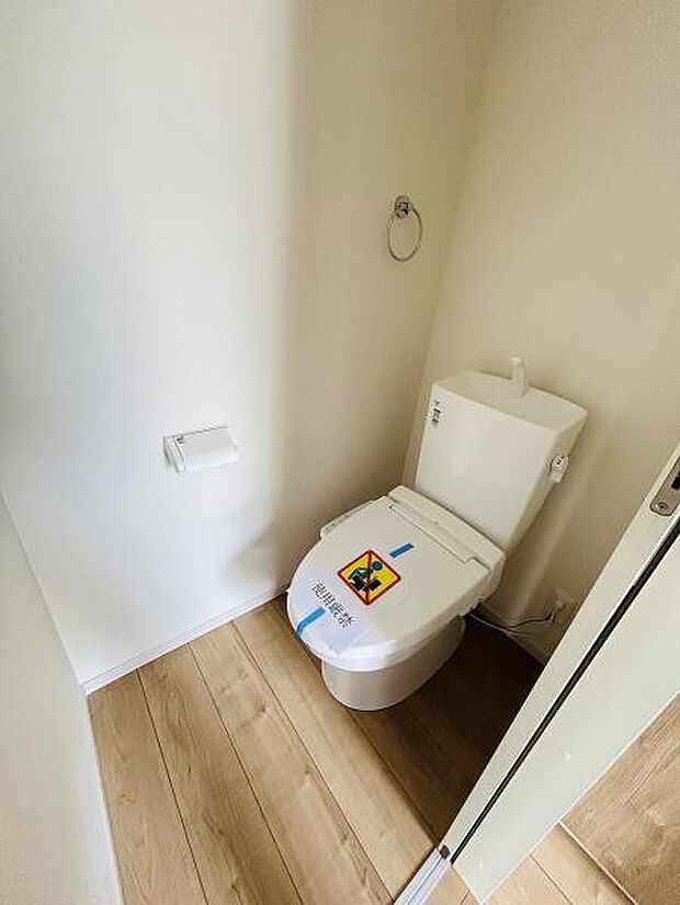 シンプルなデザインで清潔感のあるトイレ空間です。床材と壁の色合いが調和しすっきりとした印象を与えます。スペースにゆとりが感じられます。日々のお手入れもしやすい配置です。