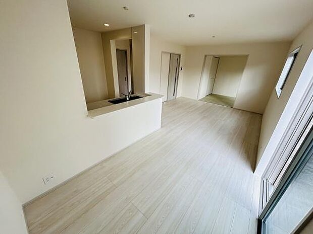 リビングには大きな窓があり明るい光が差し込みます。床材はナチュラルな色合いで清潔感のある空間です。キッチンとの仕切りもありメリハリのあるレイアウトです。全体的に広さを感じられる設計になっています。