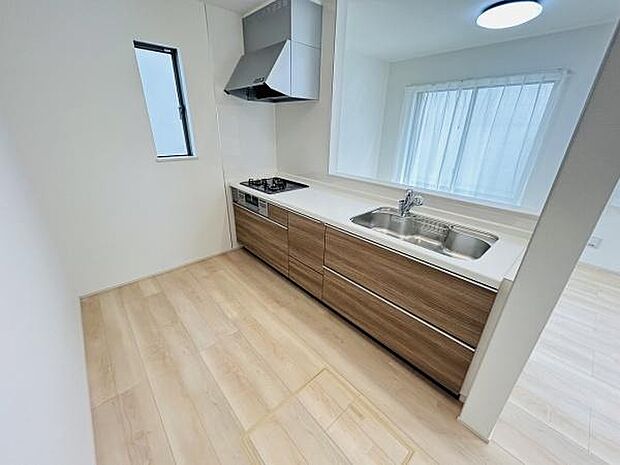 木目調のデザインが特徴的なキッチンです。収納スペースも豊富ですっきりとした印象です。窓から光が入り明るい空間となっています。清潔感のある内装が魅力です。カウンターキッチン仕様です。