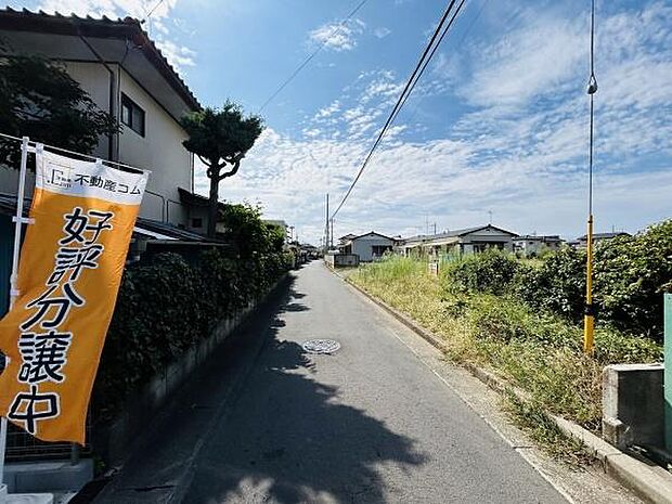 現地周辺は見通しの良い前面道路が広がっており開放感があります。車両の通行や移動もスムーズに行えます。周囲には住宅や緑があり住環境が整っています。日差しもよく差し込み明るい印象を感じられます。