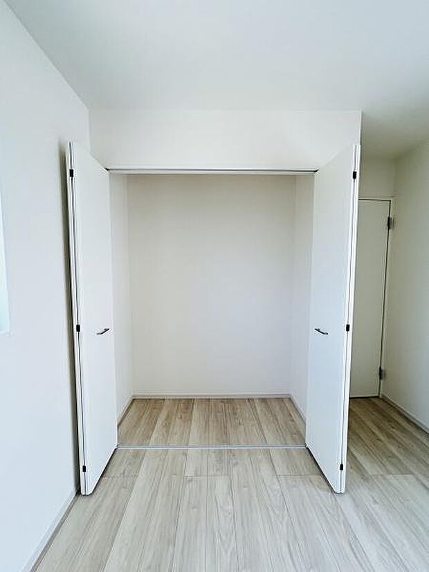 白を基調としたクローゼットが空間をすっきりと見せます。両開き扉で中の物の出し入れがしやすい仕様です。壁面いっぱいのスペースを有効活用できます。床まで明るい木目調で全体的に統一感があります。