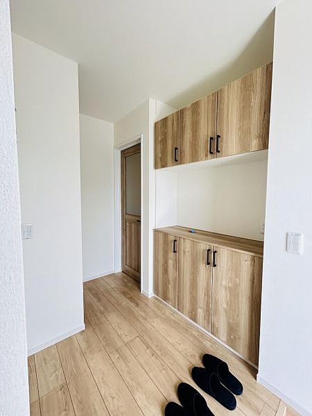 木目調の収納が玄関スペースにしっかりと設置されています。明るいフローリングと白い壁が開放感を演出します。玄関スペースがすっきりとまとまっており使い勝手の良さが感じられます。