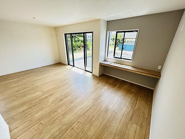 リビングは大きな窓から光が差し込む明るい空間です。木目調の床が柔らかな印象を与えています。カウンタースペースも設けられており多用途に活用できます。広さを感じさせるレイアウトが魅力です。