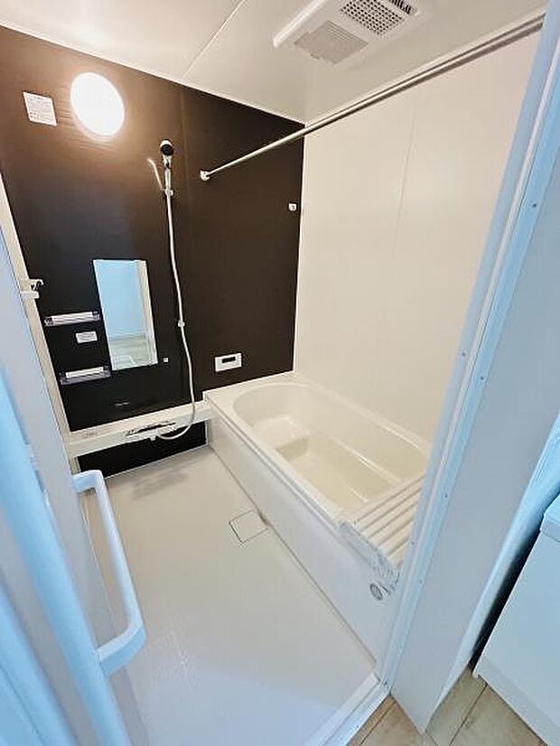 浴室は清潔感のある配色でまとめられております。手すりも設置されており安全に配慮された設計です。ミラーやシャワーの配置が使いやすい印象です。浴槽もゆったりとした形状でリラックスできます。