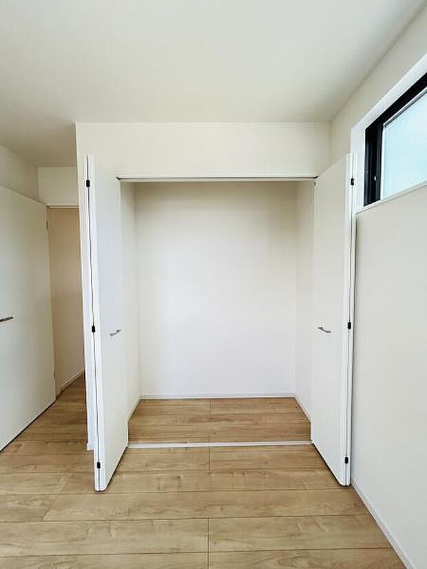 白を基調としたシンプルな収納スペースです。床までしっかり使える仕様でお部屋全体がすっきり見えます。両開き扉で開口部が広く使いやすさが感じられます。窓から自然光が差し込む明るい空間です。