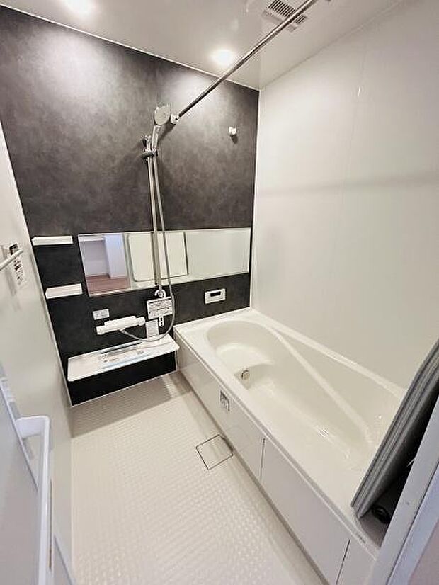 浴室は白とダークカラーのコントラストが特徴的でモダンな印象です。大きめの鏡が設置されており空間が広く見えます。清潔感のある床面でお手入れもしやすそうです。シンプルなデザインでまとめられています。