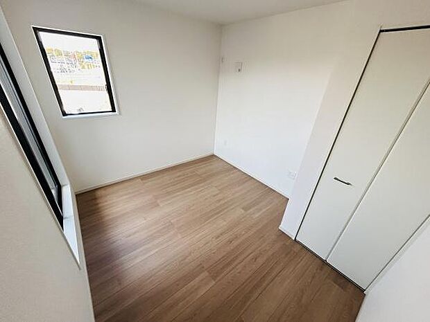 明るい2面採光が特徴の洋室です。シンプルな内装で様々なインテリアに合わせやすくなっています。クローゼット付きで収納スペースも確保されています。ナチュラルな床材が落ち着いた印象を与えます。