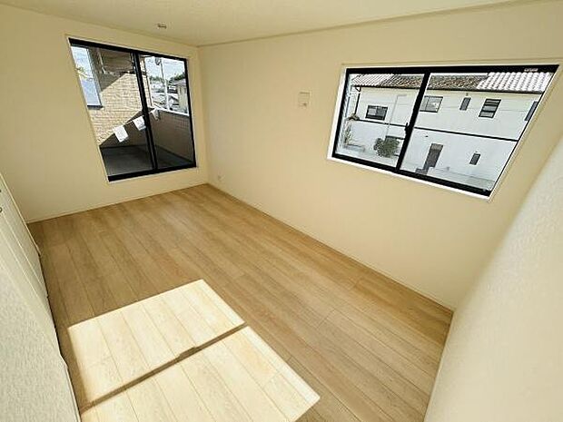 大きな窓から明るい光が差し込む寝室です。白を基調とした壁と木目調の床が空間をすっきりと見せます。清潔感のある雰囲気でゆったりとした気分で過ごせます。2面採光で換気もしやすい設計です。