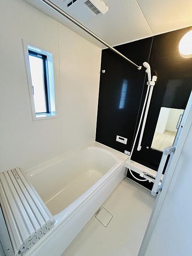 清潔感のあるホワイトとシックなブラックのコントラストが特徴のバスルームです。窓からは自然光が差し込み明るい空間となっています。浴槽はゆったりとしたサイズでリラックスできる設計です。