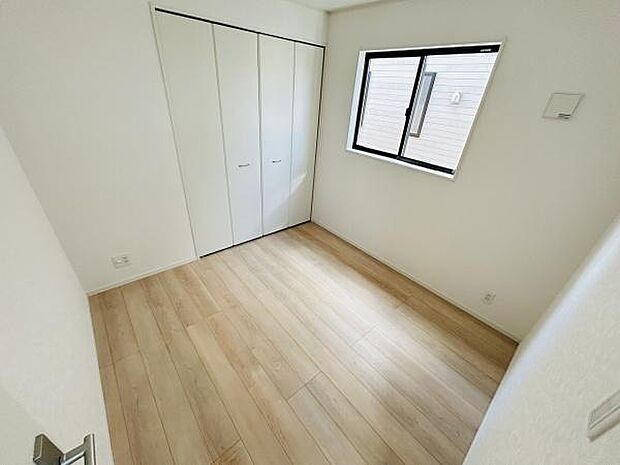明るいフローリングと白を基調とした壁が調和する洋室です。窓から自然光が差し込み清潔感のある空間となっています。収納スペースも備えられておりすっきりとした印象です。過ごしやすいレイアウトになっています。