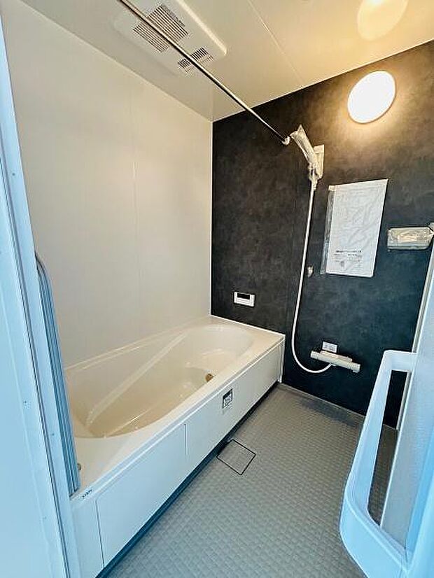 清潔感のあるバスルームです。浴槽と洗い場がゆったりと設計されています。壁面のダークカラーが空間を引き締めています。照明も明るく使いやすい印象です。全体的にお手入れしやすい造りです。