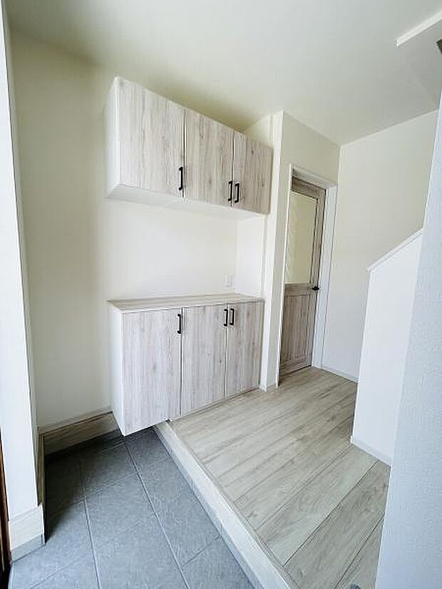 清潔感のある明るい玄関です。木目調の収納が空間に統一感を与えています。段差が緩やかで使いやすい設計です。収納スペースも豊富に確保されています。玄関ホールがすっきりとしています。