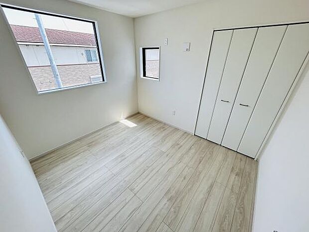 白を基調とした明るい洋室です。二面採光で室内がさらに開放的に感じられます。収納スペースも備え付けられています。床材のデザインがシンプルで統一感があります。落ち着いた雰囲気の空間です。