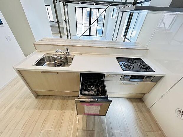 明るい空間に設置されたキッチンです。食洗機やグリル付きコンロが備わっています。ゆとりある作業スペースが魅力です。収納スペースも豊富に用意されています。水回りの手入れもしやすい仕様です。