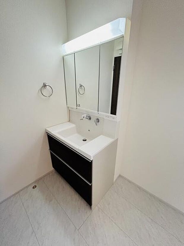 明るい照明がついた洗面台で日々の身支度に便利です。収納スペースがしっかり確保されており整理整頓に役立ちます。清潔感のある空間が印象的です。大きな鏡で使いやすさを感じられます。
