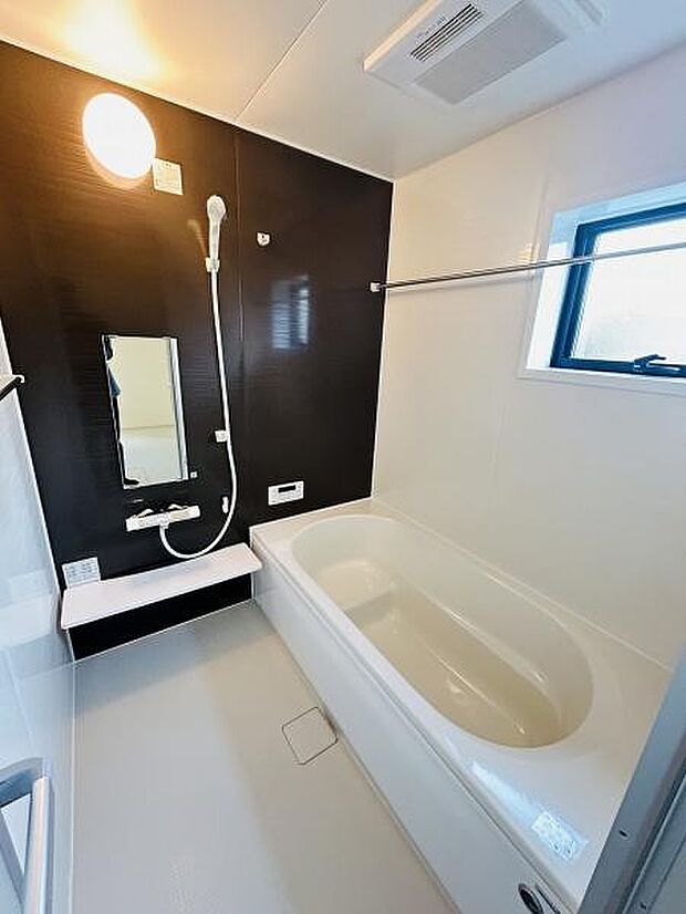 落ち着きのある色使いで清潔感が感じられるバスルームです。広めの浴槽が印象的で空間にゆとりがあります。浴室乾燥機や窓があり換気や湿気対策も配慮されています。シンプルなデザインが魅力です。