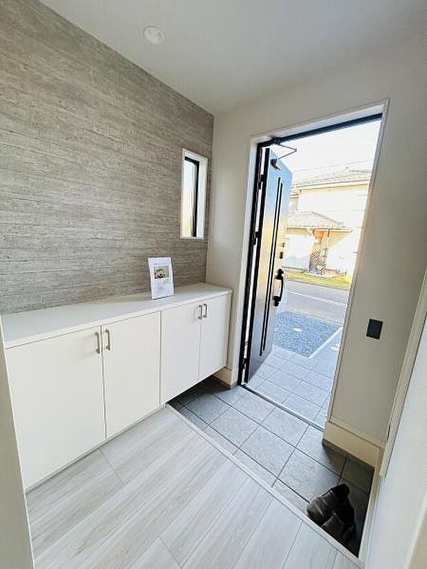 玄関は明るく開放感のある空間です。シンプルなデザインの収納が設けられており使いやすい印象です。縦長の窓から自然光が差し込み玄関全体が明るくなっています。床はお手入れしやすい素材で清潔感があります。