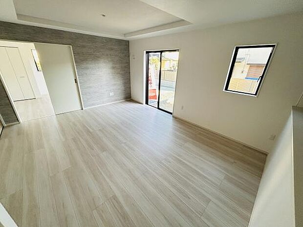 明るい色合いのフローリングが特徴のリビングです。窓から自然光がたっぷり入り室内は開放的な印象です。隣接するスペースとつながりやすい間取りとなっています。壁面のデザインクロスがアクセントになっています。