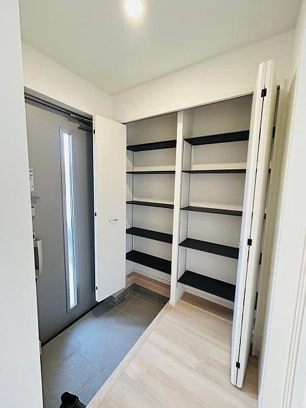 玄関は明るく開放感のある空間です。広々としたシューズインクロークが備わっています。使いやすい棚が複数設置されており収納スペースが充実しています。スッキリとした印象の玄関です。