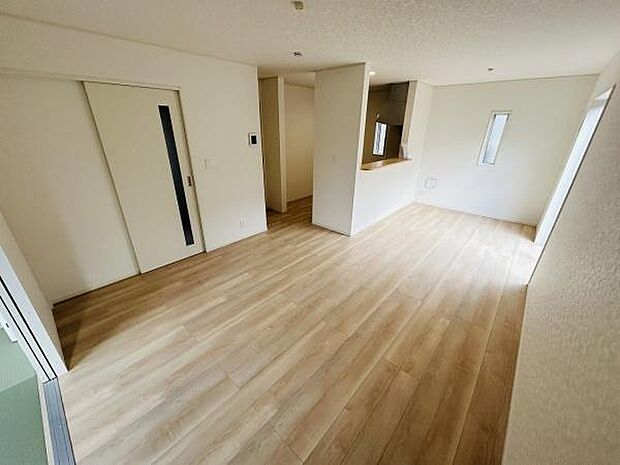 リビングは明るい色合いのフローリングが広がり開放感のある空間です。キッチンとの仕切りもスッキリしており室内の動線が良好です。スライドドアが採用されているため空間の使い方に柔軟性があります。