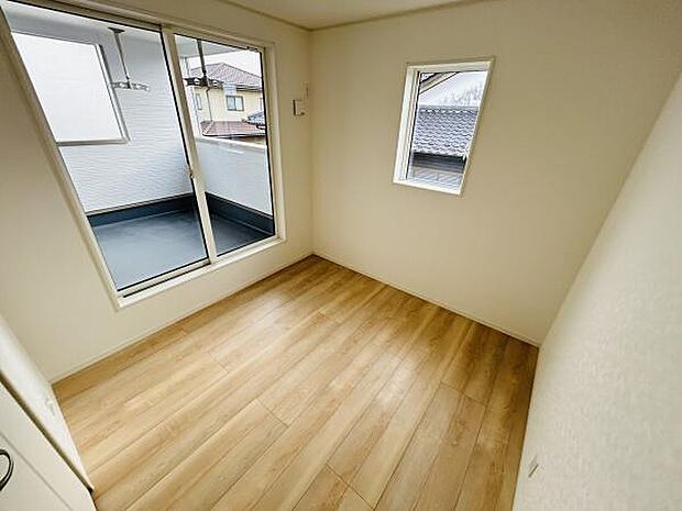 大きな窓からしっかりと自然光が入る洋室です。床は落ち着きのある木目調で室内が明るくすっきりとしています。スライドドアからはバルコニーにもアクセス可能です。コンパクトながらも機能的な空間です。