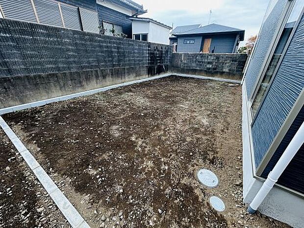 ゆったりとしたスペースが広がる庭です。シンプルな形状でお手入れやアレンジがしやすい印象です。塀があるため周囲の視線が気になりにくい点もポイントです。建物との距離も適度に取られています。