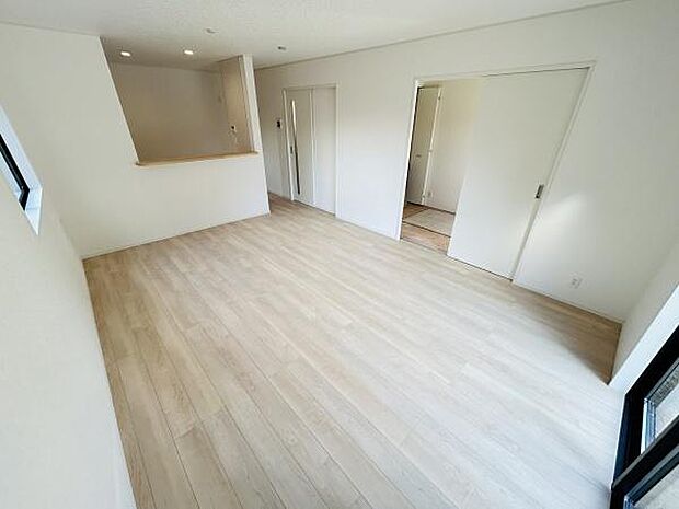 リビングは窓から自然光が差し込み明るい空間が広がっています。床材は落ち着いた色合いで清潔感ある印象です。キッチンカウンターが隣接し空間がゆったりとしています。