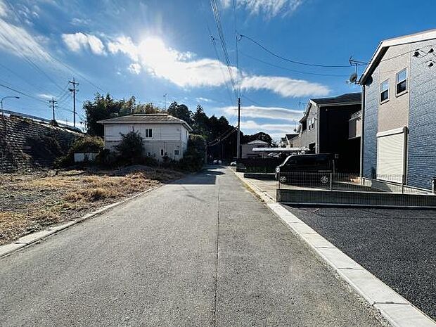 現地の前面道路は幅が広く車の通行もしやすい環境です。道路沿いは家々が整然と並び周辺は落ち着いた雰囲気です。舗装された道路で移動も快適に行えます。日当たりのよい道路環境が特徴的です。