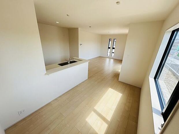 リビングは窓が大きくたっぷりと光を取り込みます。フローリングの色合いが明るく空間を広く見せます。キッチンからリビング全体を見渡せる設計です。開放感のあるレイアウトが特徴です。