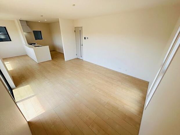 明るい光が差し込むリビングです。広々とした空間が開放感を演出しています。ナチュラルな床材が室内に統一感を与えています。キッチンとのスムーズな動線も魅力的です。