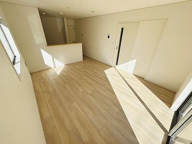 大きな窓からたっぷりと光が差し込むリビングです。ホワイトを基調とした内装が明るさを引き立てています。床材のナチュラルな色合いが空間を広く感じさせます。キッチンとのつながりもスムーズです。