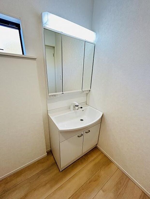 清潔感のあるデザインで毎日の身支度がしやすい洗面台です。三面鏡付きで収納スペースも豊富です。使いやすいシンプルなレイアウトが特徴です。自然光が差し込み明るい空間となっています。