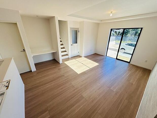 大きな窓から光が差し込む開放的な空間です。木目調のフローリングがやさしい雰囲気を演出しています。階段やデスクスペースも配置されており使い勝手の良いリビングとなっています。