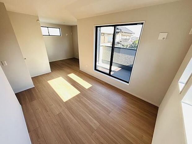 広々とした室内が特徴の寝室です。大きな窓からは日の光がしっかりと差し込みます。床は落ち着いた色合いで空間にゆとりを感じます。アクセントになる小窓も配置されています。清潔感のあるデザインです。