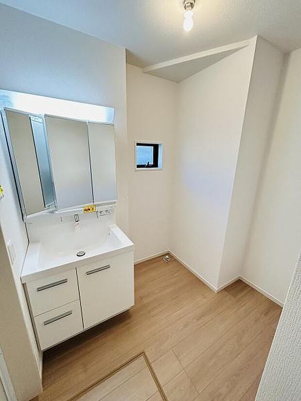 白を基調とした洗面台は清潔感があります。ミラーキャビネットが備わっており収納力も十分です。床の色合いがやわらかく空間に落ち着きを感じます。小窓から光が入り明るさを確保しています。