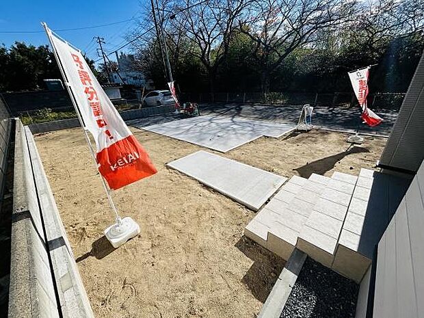 開放感のある広い庭スペースです。日当たりが良好でプライバシーもしっかり守られています。手入れしやすいシンプルな造りが特長です。複数の旗が目を引くアクセントになっています。ゆとりある空間設計が魅力です。