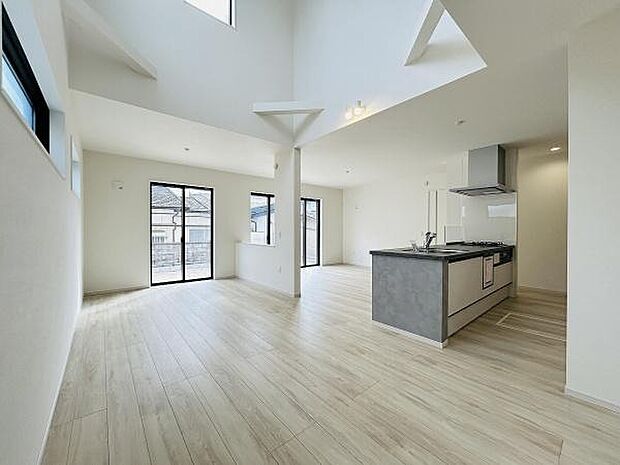 大きな窓から自然光がたっぷりと差し込むリビングです。開放感のある吹き抜け設計が魅力的です。シンプルな内装でお好みのインテリアが楽しめます。家事動線が考えられたキッチンも隣接しています。