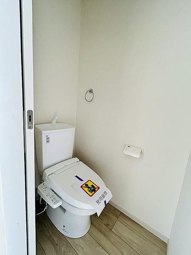 清潔感のある白を基調とした空間です。床材のナチュラルな質感が落ち着いた雰囲気を演出します。ペーパーホルダーやタオルリングが備え付けられています。温水洗浄機能付きです。