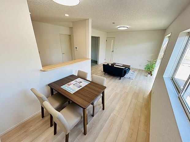 リビングは大きな窓からたっぷりと陽光が差し込み室内全体が明るい雰囲気です。床はナチュラルな色合いで空間が広く感じられます。ダイニングとリビングの一体感があり動線もスムーズです。