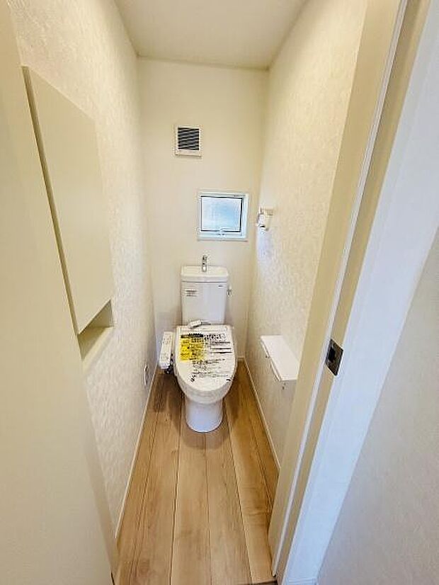 トイレには小窓と換気扇が付いており明るさと換気に配慮されています。白を基調とした内装で清潔感があります。床は木目調で落ち着いた雰囲気を演出しています。