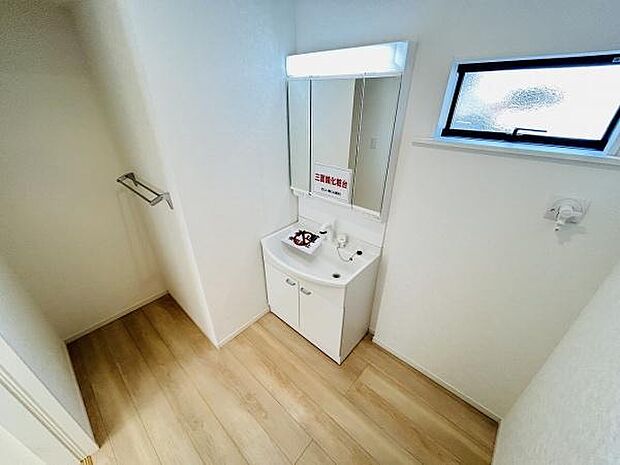 明るい洗面台が備わっており収納スペースも確保されています。清潔感を感じる空間が広がります。窓からの採光も魅力的です。照明付きのミラーで使い勝手も良好です。