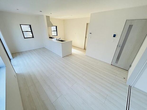 白を基調とした内装がリビング全体に広がりを感じさせます。2面の窓からたっぷりと自然光が差し込みます。キッチンとリビングが一体化したオープンな空間です。ドアや設備もシンプルで洗練された印象です。