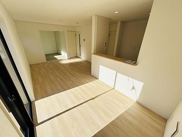 リビングは明るい日差しが差し込む空間です。開放感のあるレイアウトが特徴です。木目調の床が落ち着いた雰囲気を演出しています。室内はシンプルなデザインです。収納部分も設けられています。