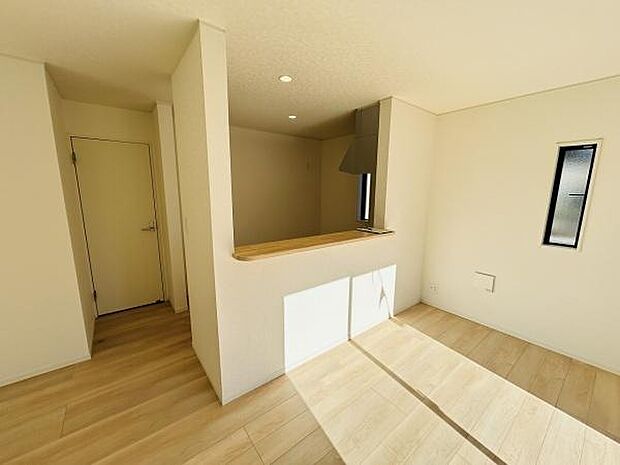 カウンター付きのキッチンが特徴的です。室内は明るい日差しが差し込む設計となっています。床の色合いと壁の白さが調和し開放感があります。シンプルなデザインで使いやすさも感じられます。