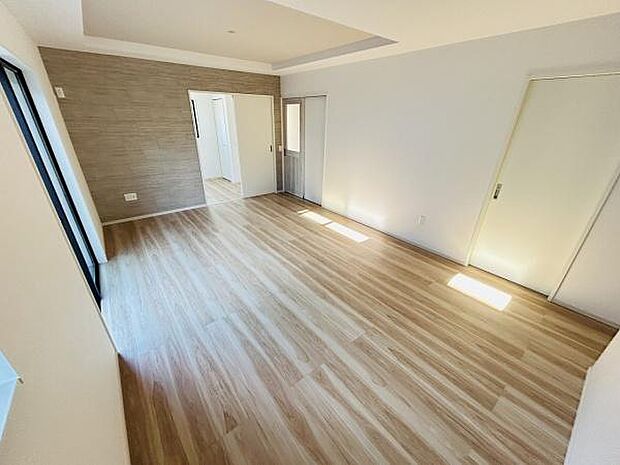 明るい光が差し込むリビングです。木目調のフローリングが空間を広々と感じさせます。シンプルな内装で様々なインテリアに調和しやすいです。壁のアクセントクロスがデザインのポイントです。