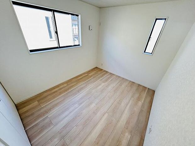 明るい光が差し込む洋室です。二面採光で室内がしっかりと照らされます。シンプルな内装が様々なインテリアに調和します。床は木目調で落ち着いた雰囲気です。収納スペースも確保されています。