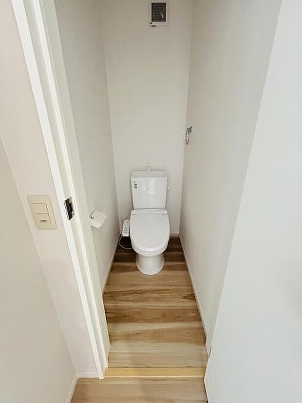 明るい色合いの床材が使われており清潔感のあるトイレ空間です。シンプルなデザインで使いやすさが感じられます。壁やドアも明るい色でまとめられていて空間がすっきりと見えます。